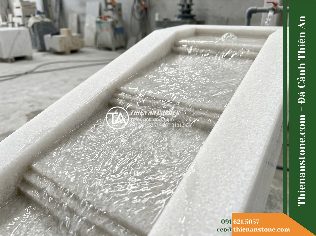 Đài Phun Khối Suối Dốc Chảy Róc Rách, D90cm Cao 85cm - Hình 7 Đài Phun Khối Suối Dốc Chảy Róc Rách, D90cm Cao 85cm - A realistic close-up shot of water flowing down the inclined carved stone path o