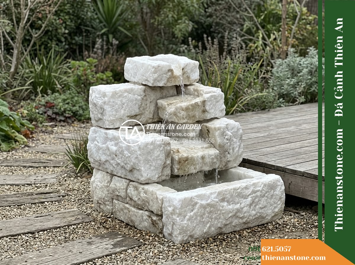 Đài Phun Khối Suối Xếp Tầng Mộc Mạc, D70cm Cao 80cm - Hình 5 Đài Phun Khối Suối Xếp Tầng Mộc Mạc, D70cm Cao 80cm - Wide view of the D70cm H80cm stone fountain placed near a low-rise modern wooden