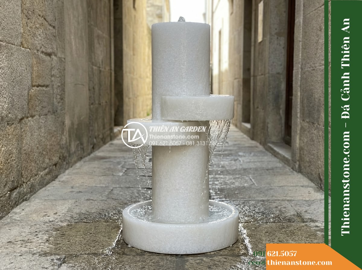 Đài Phun Lu Nước Xếp 2 Tầng Lệch, D40cm Cao 90cm - Hình 12 Đài Phun Lu Nước Xếp 2 Tầng Lệch, D40cm Cao 90cm - Wide view of the slender vertical stone fountain placed in a tight walkway corri