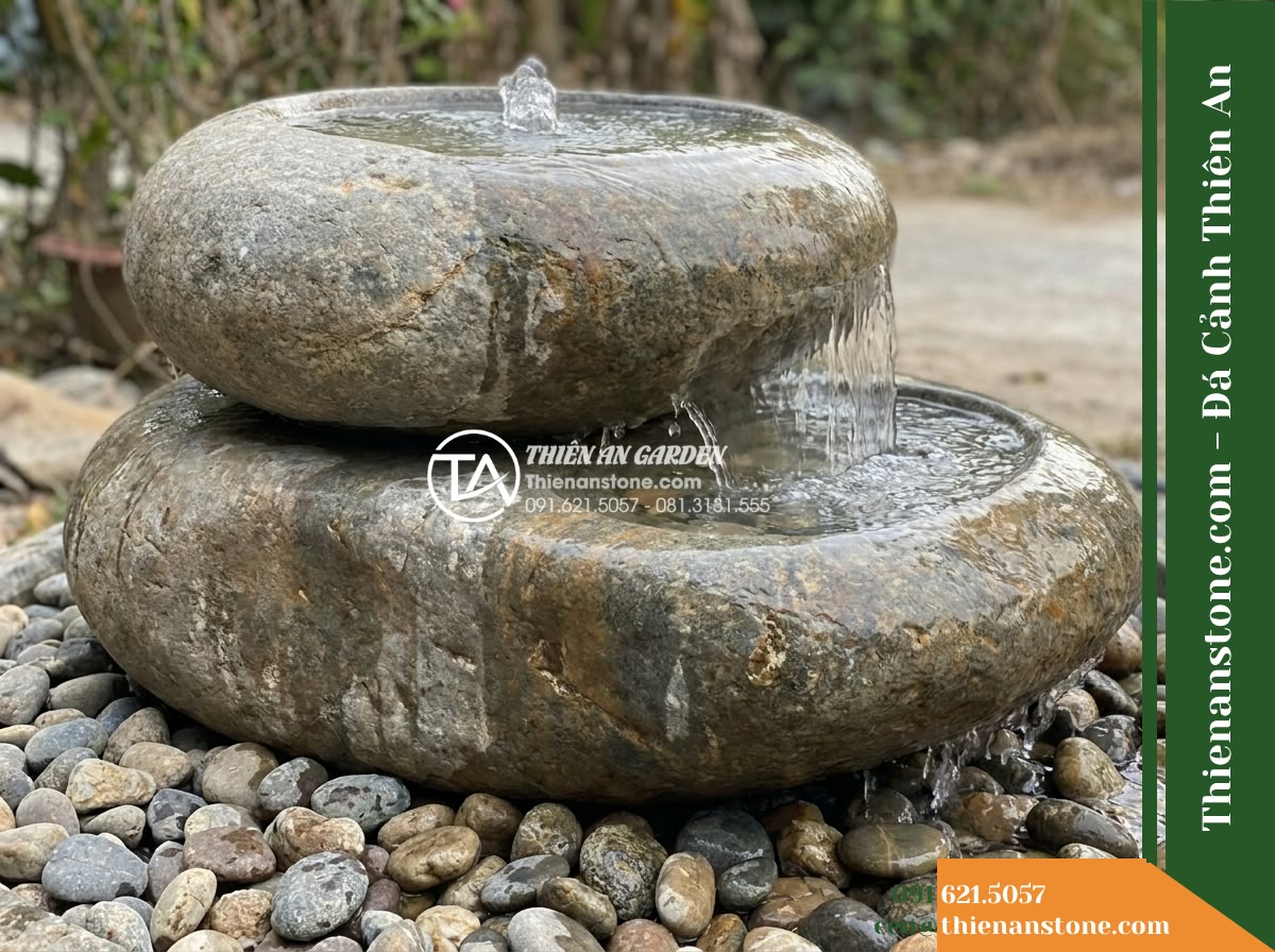 Đài Phun Sỏi Biển Bo Tròn Xếp Xéo, D70cm Cao 1.1m - Hình 8 Đài Phun Sỏi Biển Bo Tròn Xếp Xéo, D70cm Cao 1.1m - Side angle close-up showing water overflowing from the upper rounded stone pebbl