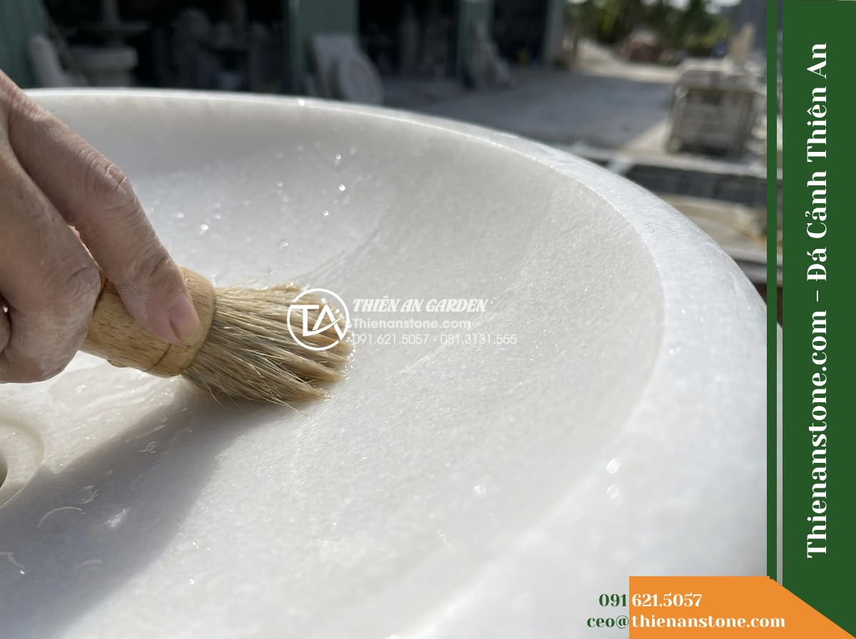 Đài Phun Trắng Ngọc Chân Vuông Mịn, Bát D1.1m Cao 1.5m - Hình 15 Đài Phun Trắng Ngọc Chân Vuông Mịn, Bát D1.1m Cao 1.5m - Close-up macro shot of routine maintenance on the stone fountain, showing a hand