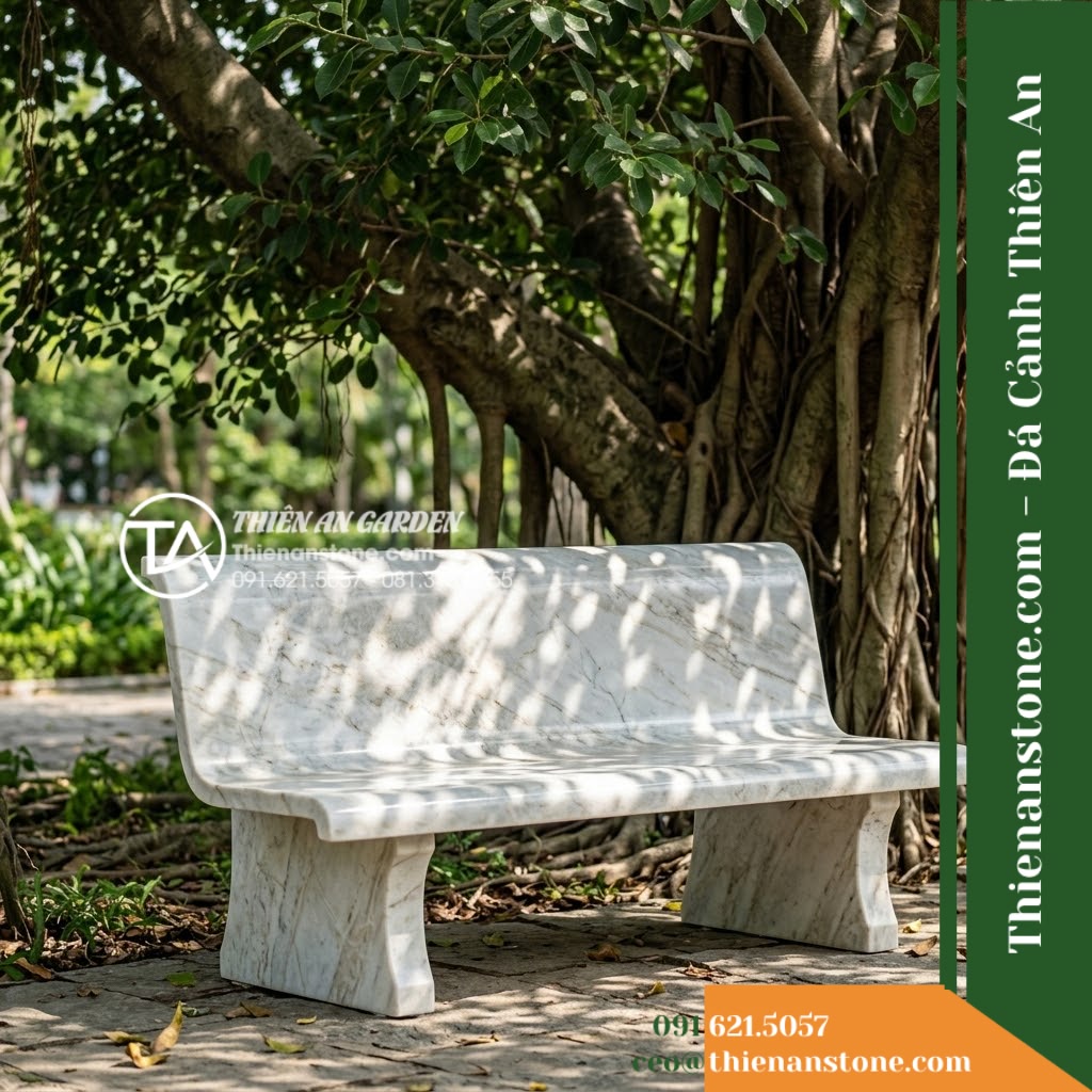 Ghế Đá Công Viên Có Tựa Bản Rộng Thiên Thanh 180x55x88cm - Đá Trắng Cẩm Thạch - Hình 2 Ghế Đá Công Viên Có Tựa Bản Rộng Thiên Thanh 180x55x88cm - Đá Trắng Cẩm Thạch - A beautifully crafted white marble stone bench under a large banyan tree, dapple