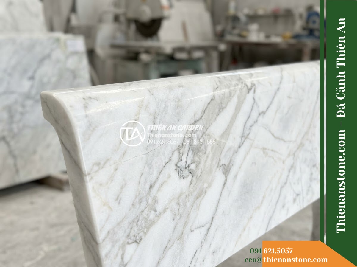 Ghế Đá Công Viên Có Tựa Cong Huyền Vũ 150x50x85cm - Đá Đen Cẩm Thạch - Hình 3 Ghế Đá Công Viên Có Tựa Cong Huyền Vũ 150x50x85cm - Đá Đen Cẩm Thạch - A black marble stone bench at golden hour, warm sunset light casting long shadow