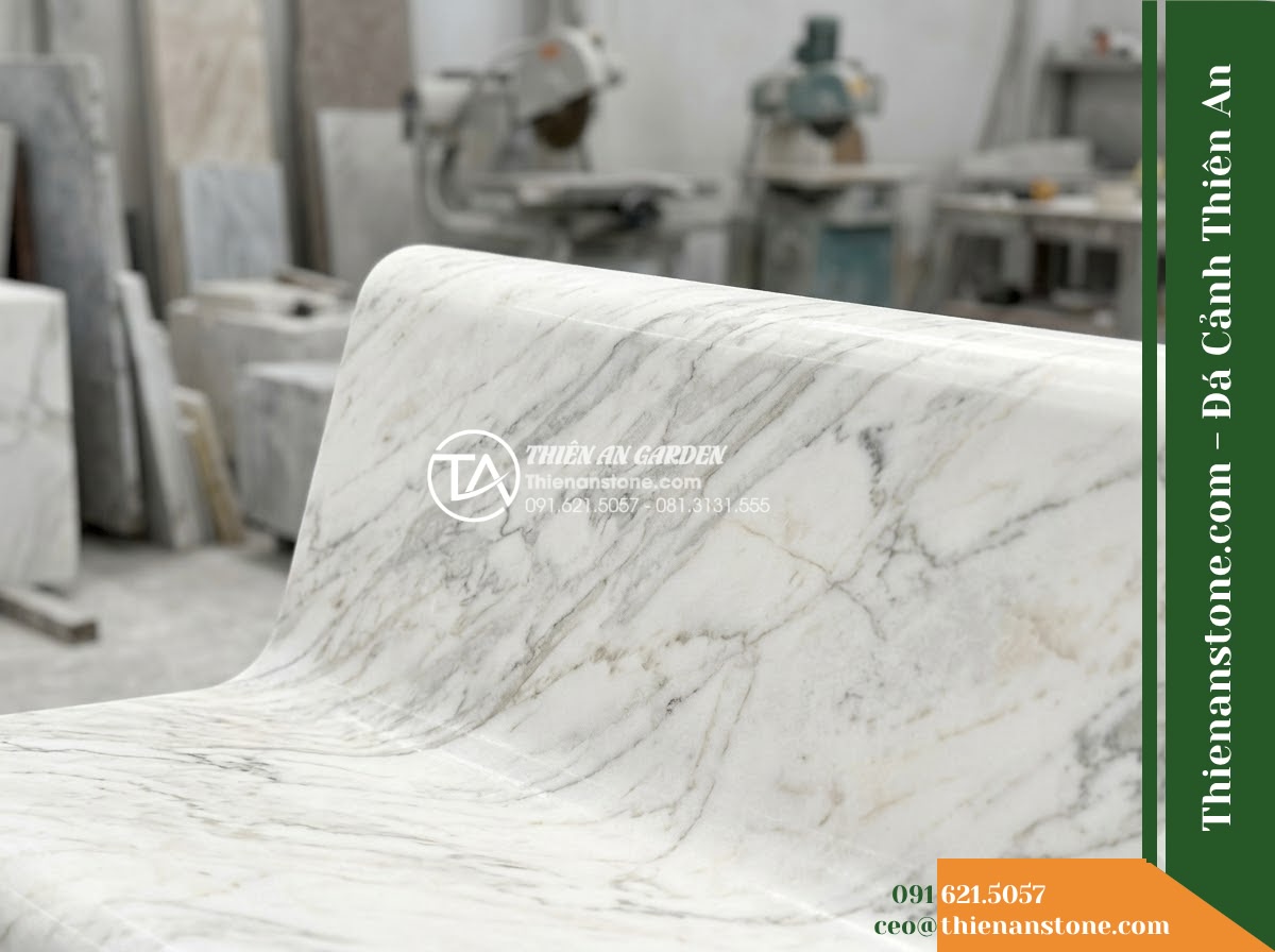 Ghế Đá Công Viên Có Tựa Nan Dọc Minh Đức 150x50x88cm - Đá Đen Cẩm Thạch - Hình 3 Ghế Đá Công Viên Có Tựa Nan Dọc Minh Đức 150x50x88cm - Đá Đen Cẩm Thạch - Autumn scene with fallen leaves scattered on a black marble stone bench in a pea