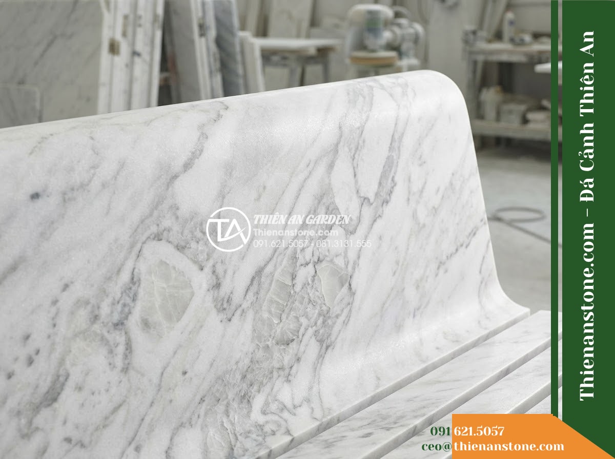 Ghế Đá Công Viên Có Tựa Song Ngang Gia Hưng 150x50x88cm - Đá Vàng Cẩm Thạch - Hình 3 Ghế Đá Công Viên Có Tựa Song Ngang Gia Hưng 150x50x88cm - Đá Vàng Cẩm Thạch - Autumn scene with fallen leaves scattered on a golden marble stone bench in a pe