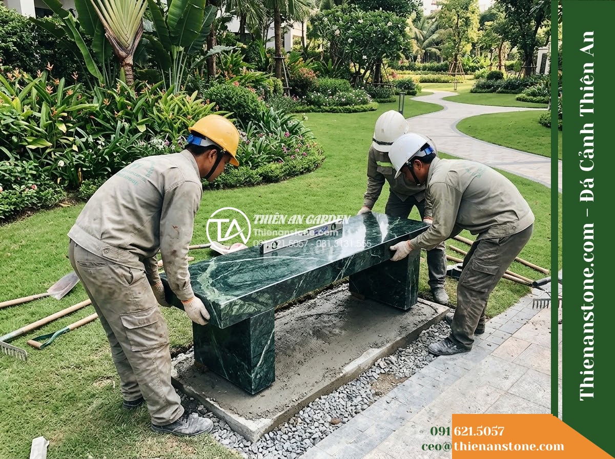 Ghế Đá Công Viên Không Tựa Chân Khối Trường Xuân 160x45x45cm - Đá Xanh Cẩm Thạch - Hình 5 Ghế Đá Công Viên Không Tựa Chân Khối Trường Xuân 160x45x45cm - Đá Xanh Cẩm Thạch - Professional installation of a green marble stone bench in a landscaped garden,