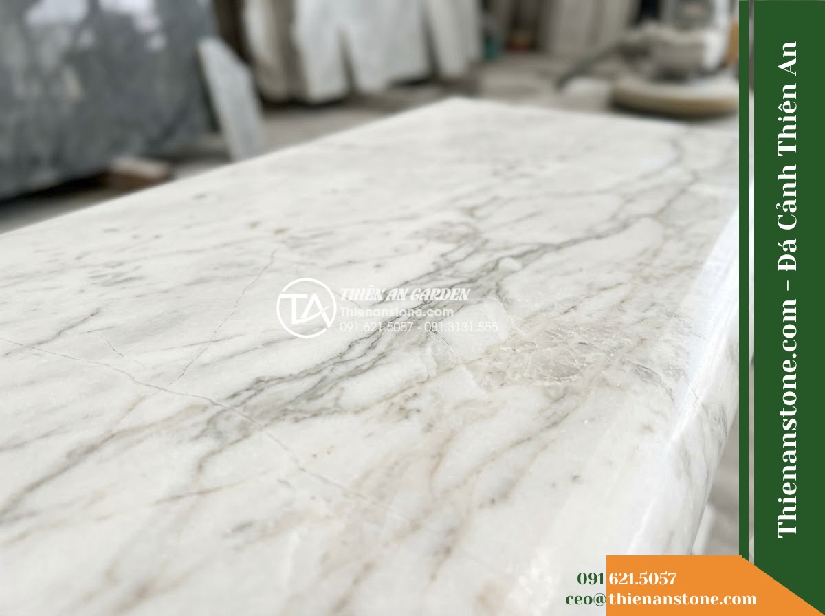 Ghế Đá Công Viên Không Tựa Chân Trụ Bình An 150x45x45cm - Đá Trắng Cẩm Thạch - Hình 5 Ghế Đá Công Viên Không Tựa Chân Trụ Bình An 150x45x45cm - Đá Trắng Cẩm Thạch - Professional installation of a white marble stone bench in a landscaped garden,