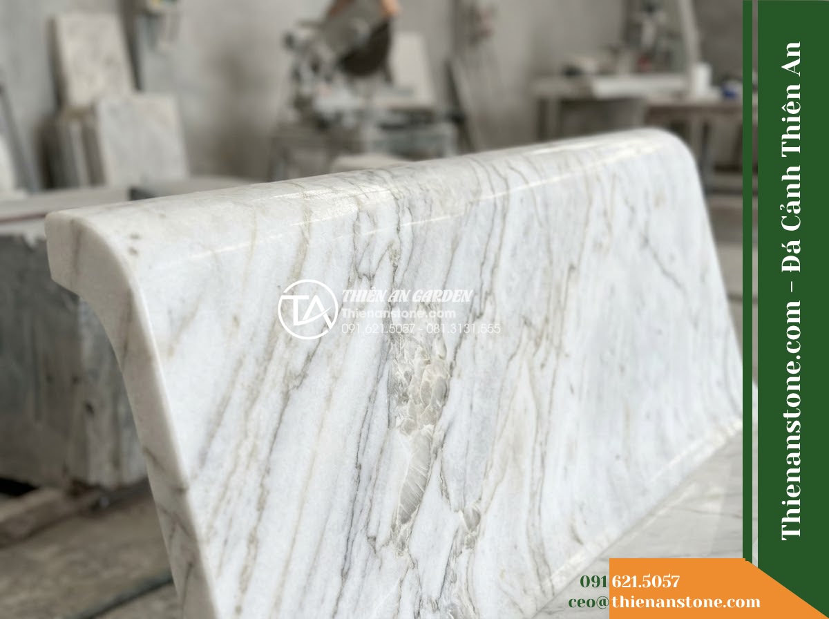 Ghế Đá Công Viên Không Tựa Dáng Vòm Thiên Sơn 140x45x45cm - Đá Xanh Cẩm Thạch - Hình 2 Ghế Đá Công Viên Không Tựa Dáng Vòm Thiên Sơn 140x45x45cm - Đá Xanh Cẩm Thạch - A green marble stone bench placed in a lush Vietnamese garden, wide angle shot s