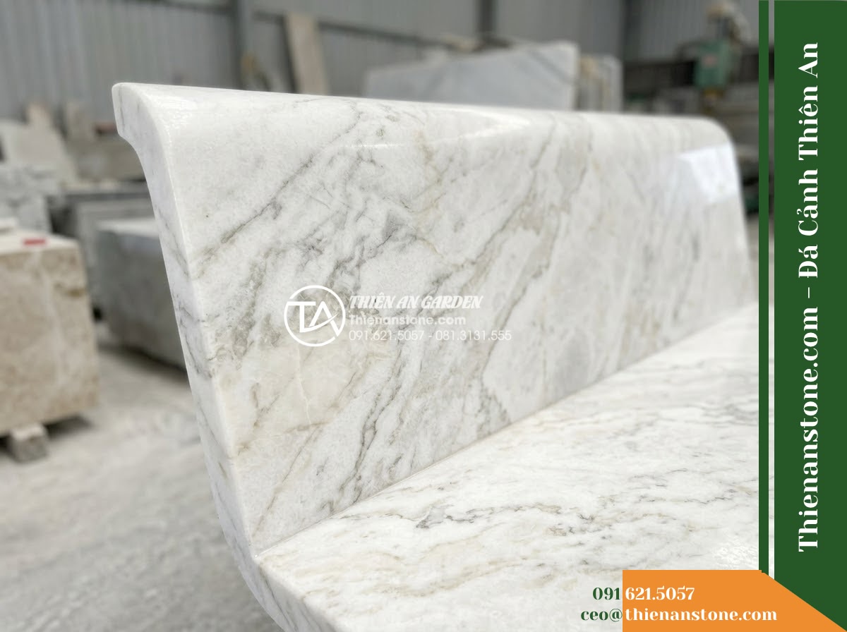 Ghế Đá Công Viên Không Tựa Mặt Cong Thanh Vân 150x45x45cm - Đá Trắng Cẩm Thạch - Hình 5 Ghế Đá Công Viên Không Tựa Mặt Cong Thanh Vân 150x45x45cm - Đá Trắng Cẩm Thạch - Professional installation of a white marble stone bench in a landscaped garden,