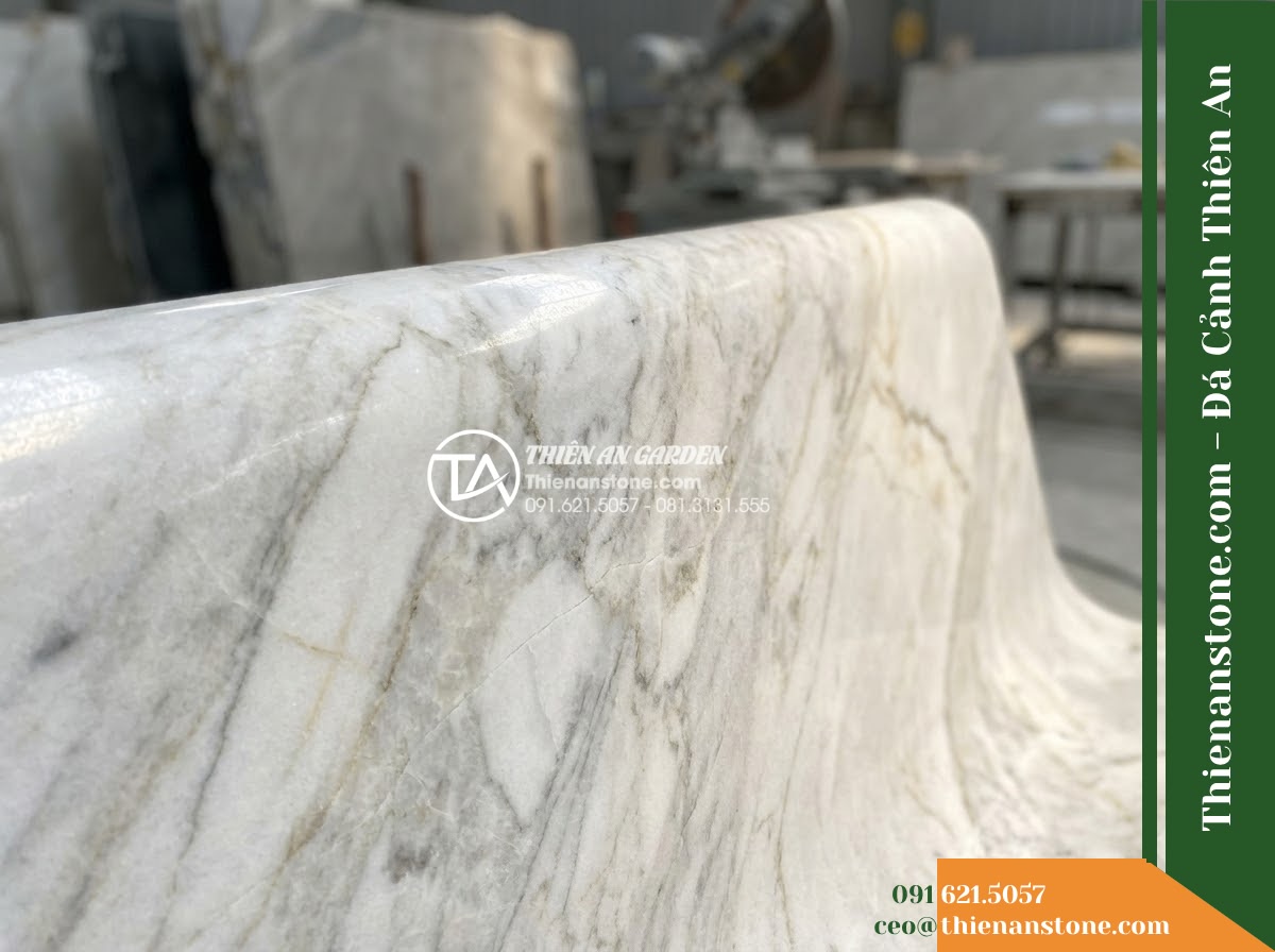 Ghế Đá Granito Thiên Thành – Kích thước 165 x 50 x 80 cm – Kiểu dáng tựa cong thấp, mặt ngồi rộng. Chất liệu đá granito (đá mài) - Hình 2 Ghế Đá Granito Thiên Thành – Kích thước 165 x 50 x 80 cm – Kiểu dáng tựa cong thấp, mặt ngồi rộng. Chất liệu đá granito (đá mài) - A granito polished stone stone bench placed in a lush Vietnamese garden, wide an