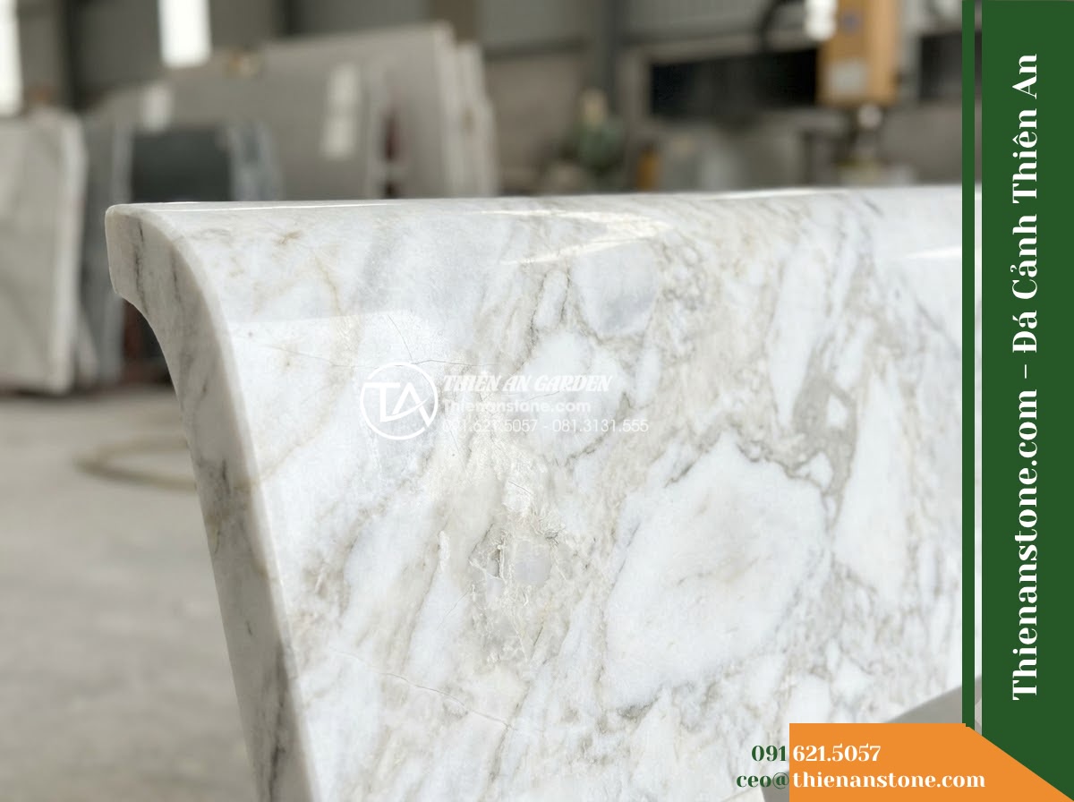Ghế Đá Sân Trường Ánh Dương – Kích thước 175 x 50 x 80 cm – Kiểu dáng tựa thẳng liền tấm, chân vuông. Chất liệu đá vàng cẩm thạch - Hình 2 Ghế Đá Sân Trường Ánh Dương – Kích thước 175 x 50 x 80 cm – Kiểu dáng tựa thẳng liền tấm, chân vuông. Chất liệu đá vàng cẩm thạch - A beautifully crafted golden marble stone bench under a large banyan tree, dappl