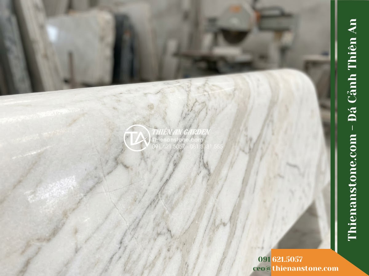 Ghế Đá Sân Trường Cánh Diều – Kích thước 150 x 48 x 78 cm – Kiểu dáng tựa nan thưa, đường nét mềm. Chất liệu đá hoa cương - Hình 2 Ghế Đá Sân Trường Cánh Diều – Kích thước 150 x 48 x 78 cm – Kiểu dáng tựa nan thưa, đường nét mềm. Chất liệu đá hoa cương - A granite stone bench placed in a lush Vietnamese garden, wide angle shot showin