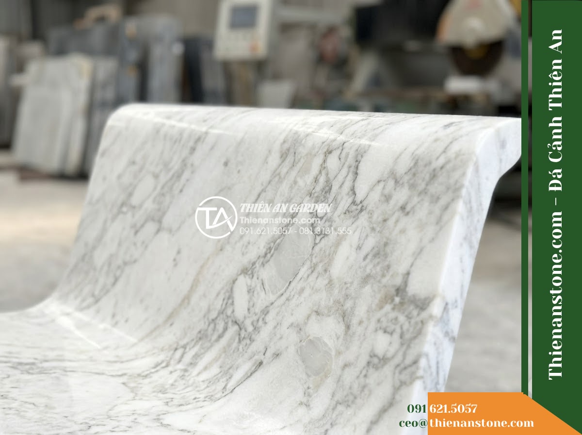 Ghế Đá Sân Trường Cánh Diều – Kích thước 150 x 48 x 78 cm – Kiểu dáng tựa nan thưa, đường nét mềm. Chất liệu đá hoa cương - Hình 5 Ghế Đá Sân Trường Cánh Diều – Kích thước 150 x 48 x 78 cm – Kiểu dáng tựa nan thưa, đường nét mềm. Chất liệu đá hoa cương - Professional installation of a granite stone bench in a landscaped garden, worke