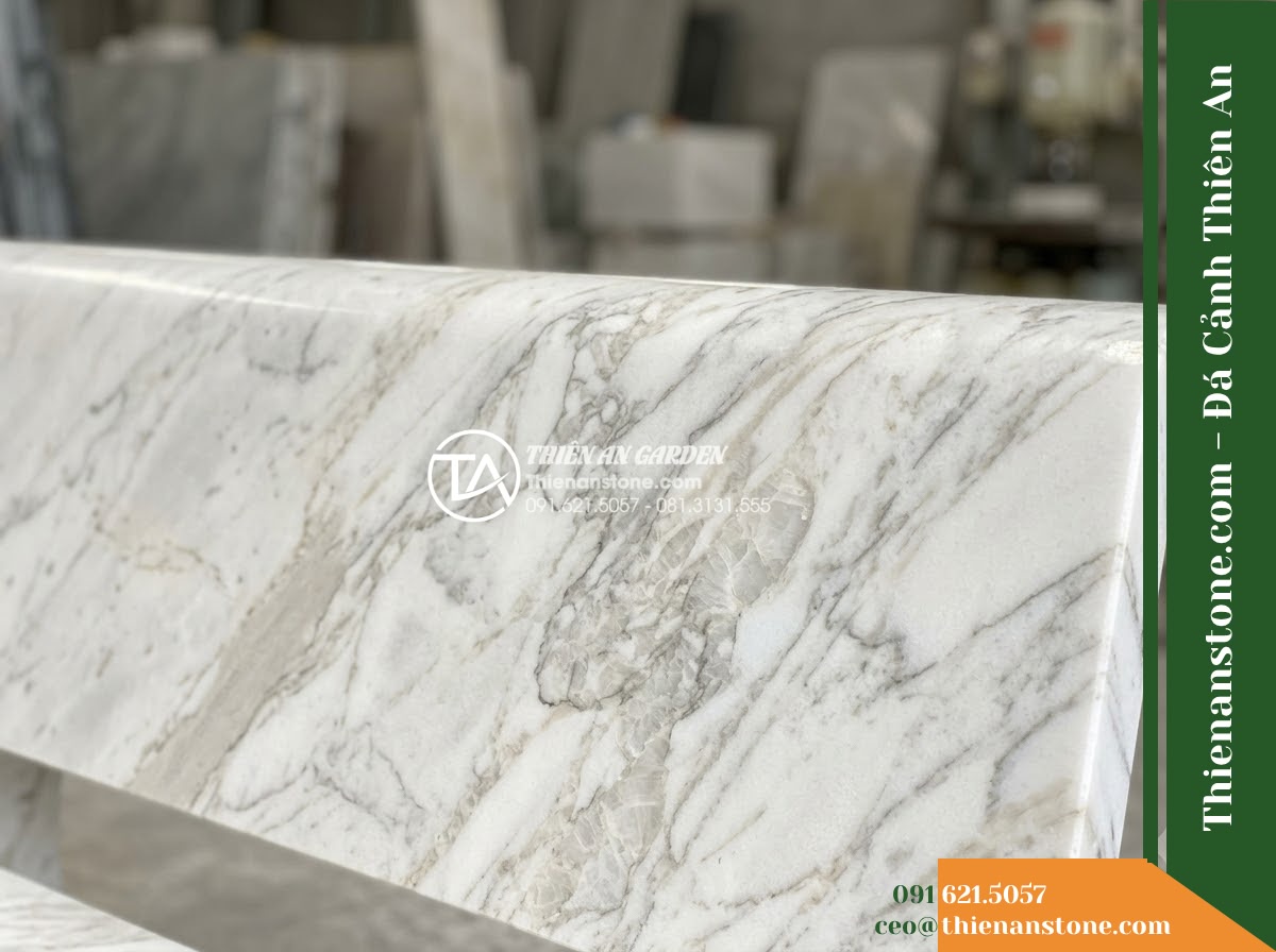 Ghế Đá Sân Trường Hành Trang – Kích thước 150 x 46 x 45 cm – Kiểu dáng băng thấp không tựa, góc bo lớn. Chất liệu đá vân mây - Hình 2 Ghế Đá Sân Trường Hành Trang – Kích thước 150 x 46 x 45 cm – Kiểu dáng băng thấp không tựa, góc bo lớn. Chất liệu đá vân mây - Elegant cloud marble stone bench in a school courtyard, flanked by phoenix flowe