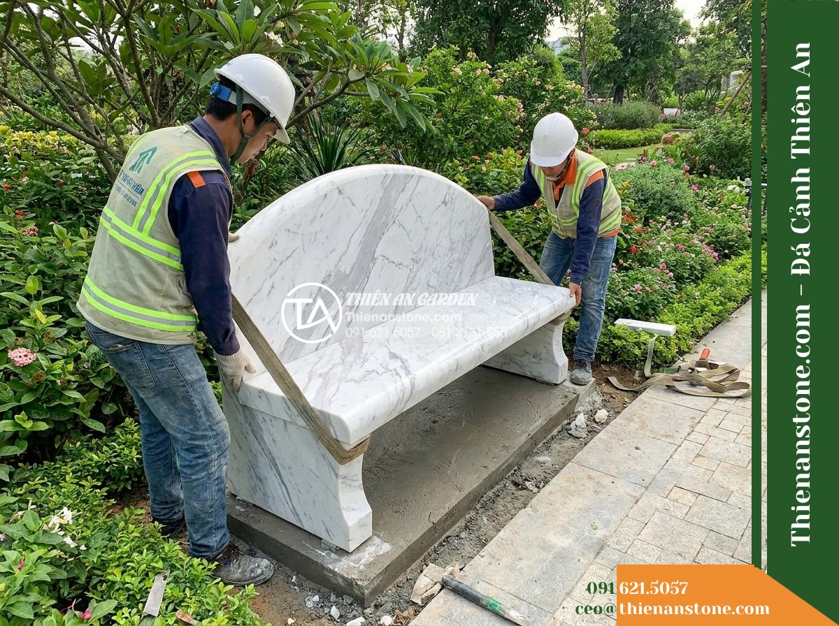 Ghế Đá Sân Trường Hoa Phượng – Kích thước 180 x 50 x 80 cm – Kiểu dáng có tựa thẳng, chân trụ chắc chắn. Chất liệu đá vàng cẩm thạch - Hình 5 Ghế Đá Sân Trường Hoa Phượng – Kích thước 180 x 50 x 80 cm – Kiểu dáng có tựa thẳng, chân trụ chắc chắn. Chất liệu đá vàng cẩm thạch - Professional installation of a golden marble stone bench in a landscaped garden,