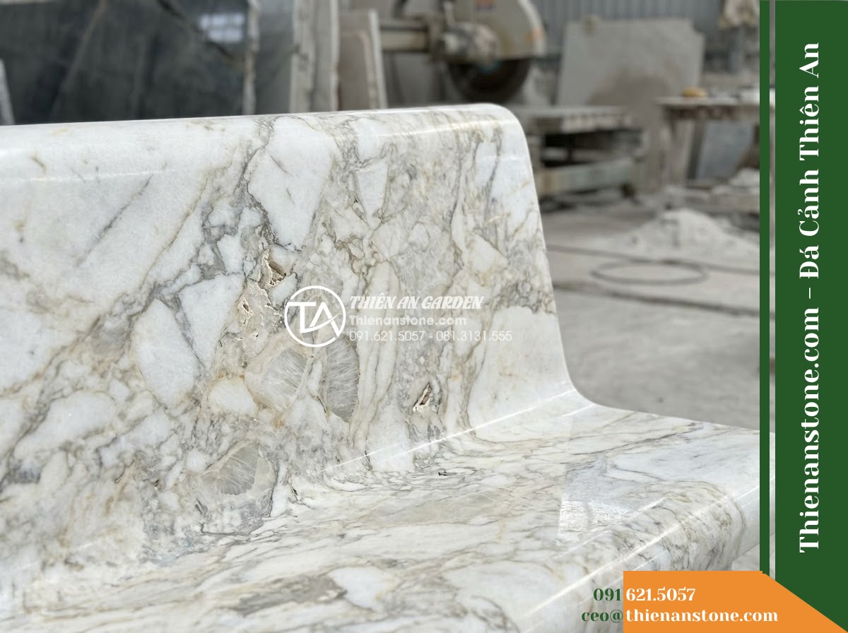 Ghế Đá Sân Trường Măng Non – Kích thước 150 x 45 x 78 cm – Kiểu dáng tựa cong nhẹ, hai đầu bo tròn. Chất liệu đá hoa cương - Hình 5 Ghế Đá Sân Trường Măng Non – Kích thước 150 x 45 x 78 cm – Kiểu dáng tựa cong nhẹ, hai đầu bo tròn. Chất liệu đá hoa cương - Professional installation of a granite stone bench in a landscaped garden, worke