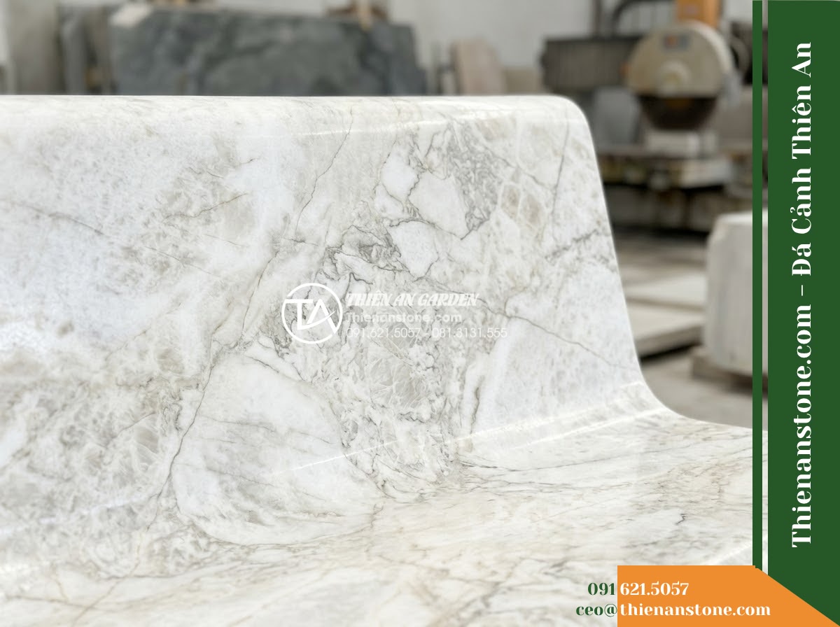 Ghế Đá Sân Trường Phượng Hồng – Kích thước 175 x 50 x 82 cm – Kiểu dáng tựa vòm rộng, chân trụ bản lớn. Chất liệu đá vàng cẩm thạch - Hình 3 Ghế Đá Sân Trường Phượng Hồng – Kích thước 175 x 50 x 82 cm – Kiểu dáng tựa vòm rộng, chân trụ bản lớn. Chất liệu đá vàng cẩm thạch - A golden marble stone bench at golden hour, warm sunset light casting long shado