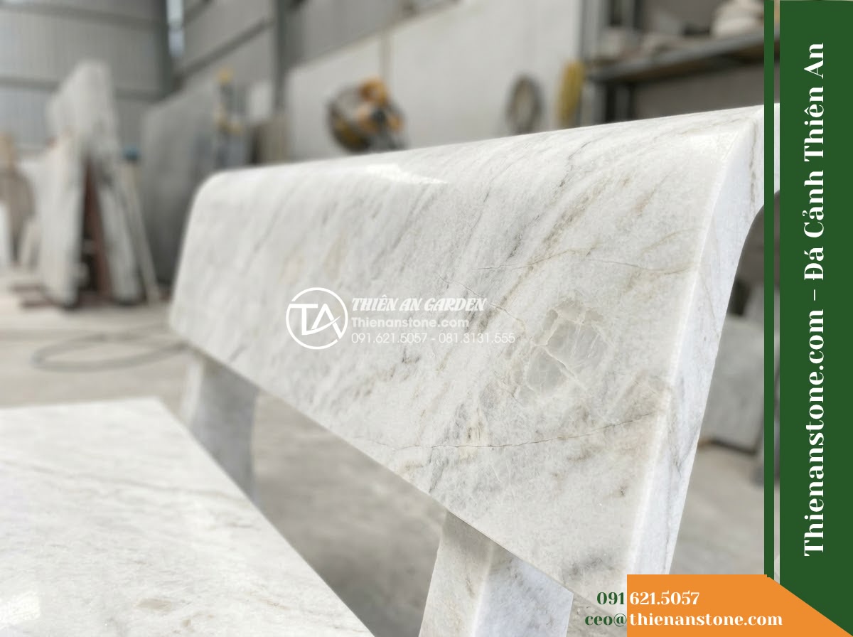 Ghế Đá Sân Trường Tri Thức – Kích thước 170 x 48 x 80 cm – Kiểu dáng tựa nan dọc, mặt ngồi rộng. Chất liệu đá vàng cẩm thạch - Hình 5 Ghế Đá Sân Trường Tri Thức – Kích thước 170 x 48 x 80 cm – Kiểu dáng tựa nan dọc, mặt ngồi rộng. Chất liệu đá vàng cẩm thạch - Professional installation of a golden marble stone bench in a landscaped garden,