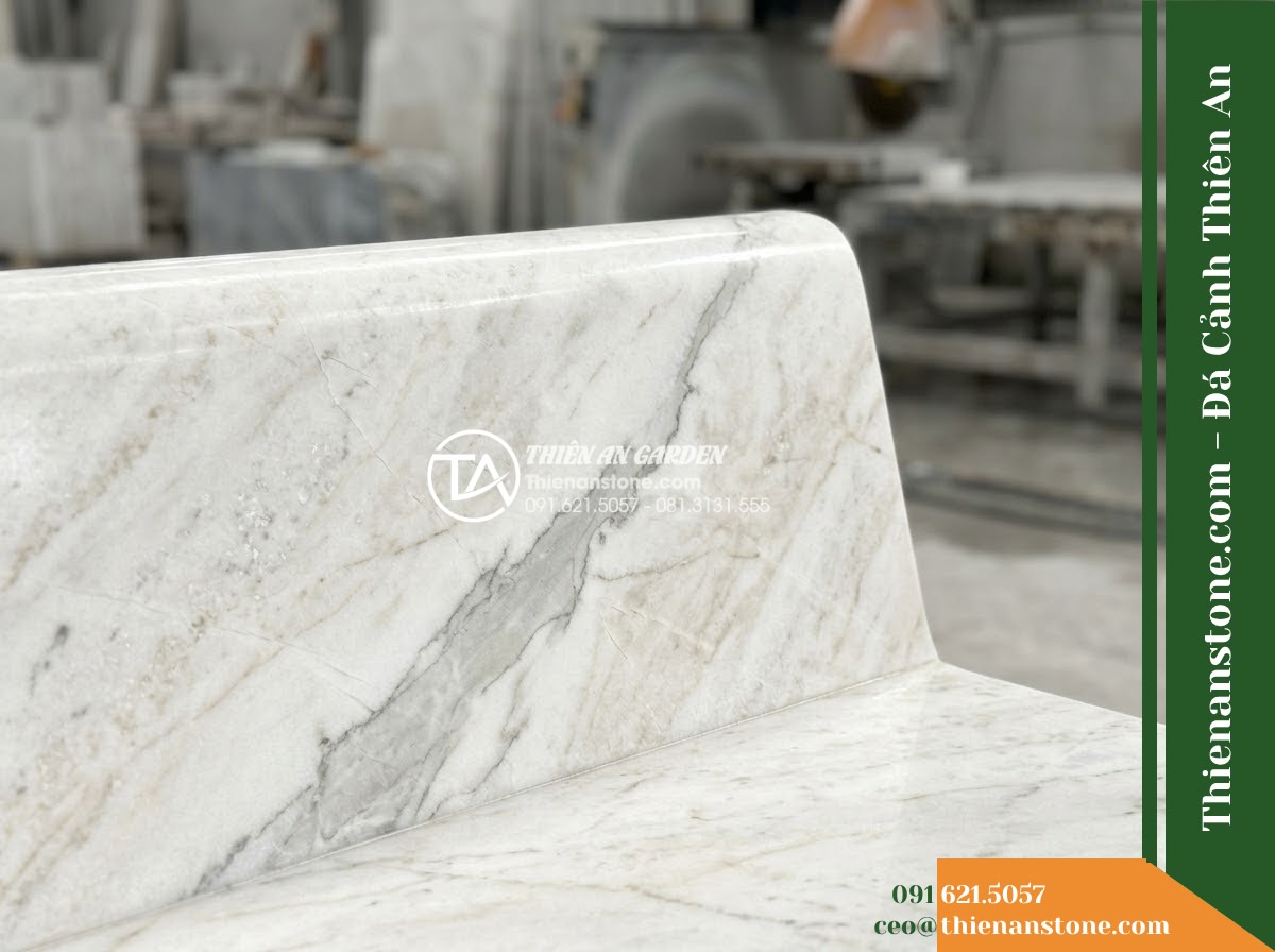 Ghế Đá Sân Trường Vững Bước – Kích thước 175 x 48 x 80 cm – Kiểu dáng tựa cong thấp, hai đầu vuông. Chất liệu đá hoa cương - Hình 2 Ghế Đá Sân Trường Vững Bước – Kích thước 175 x 48 x 80 cm – Kiểu dáng tựa cong thấp, hai đầu vuông. Chất liệu đá hoa cương - Elegant granite stone bench in a school courtyard, flanked by phoenix flower tre