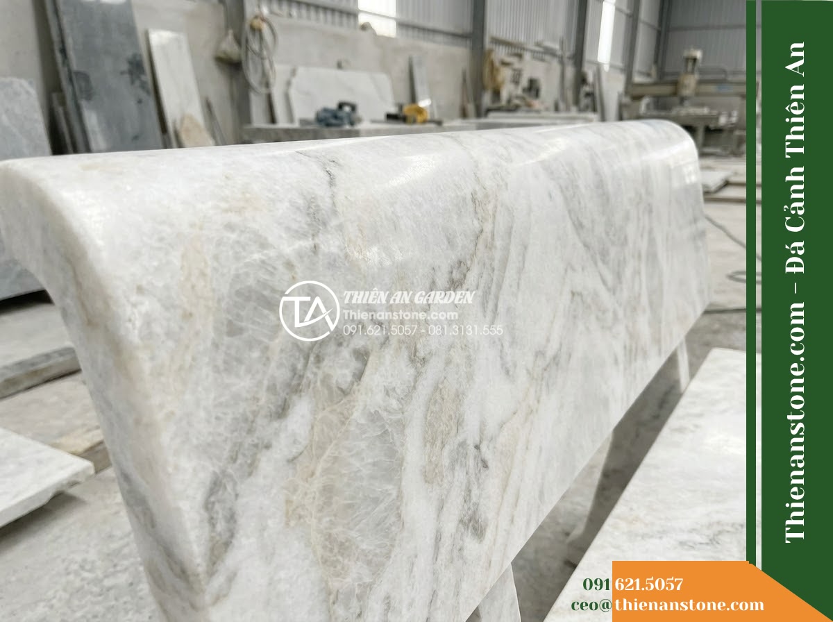 Ghế Đá Sân Trường Vững Bước – Kích thước 175 x 48 x 80 cm – Kiểu dáng tựa cong thấp, hai đầu vuông. Chất liệu đá vân mây - Hình 4 Ghế Đá Sân Trường Vững Bước – Kích thước 175 x 48 x 80 cm – Kiểu dáng tựa cong thấp, hai đầu vuông. Chất liệu đá vân mây - A cloud marble stone bench integrated into a Vietnamese luxury resort landscape