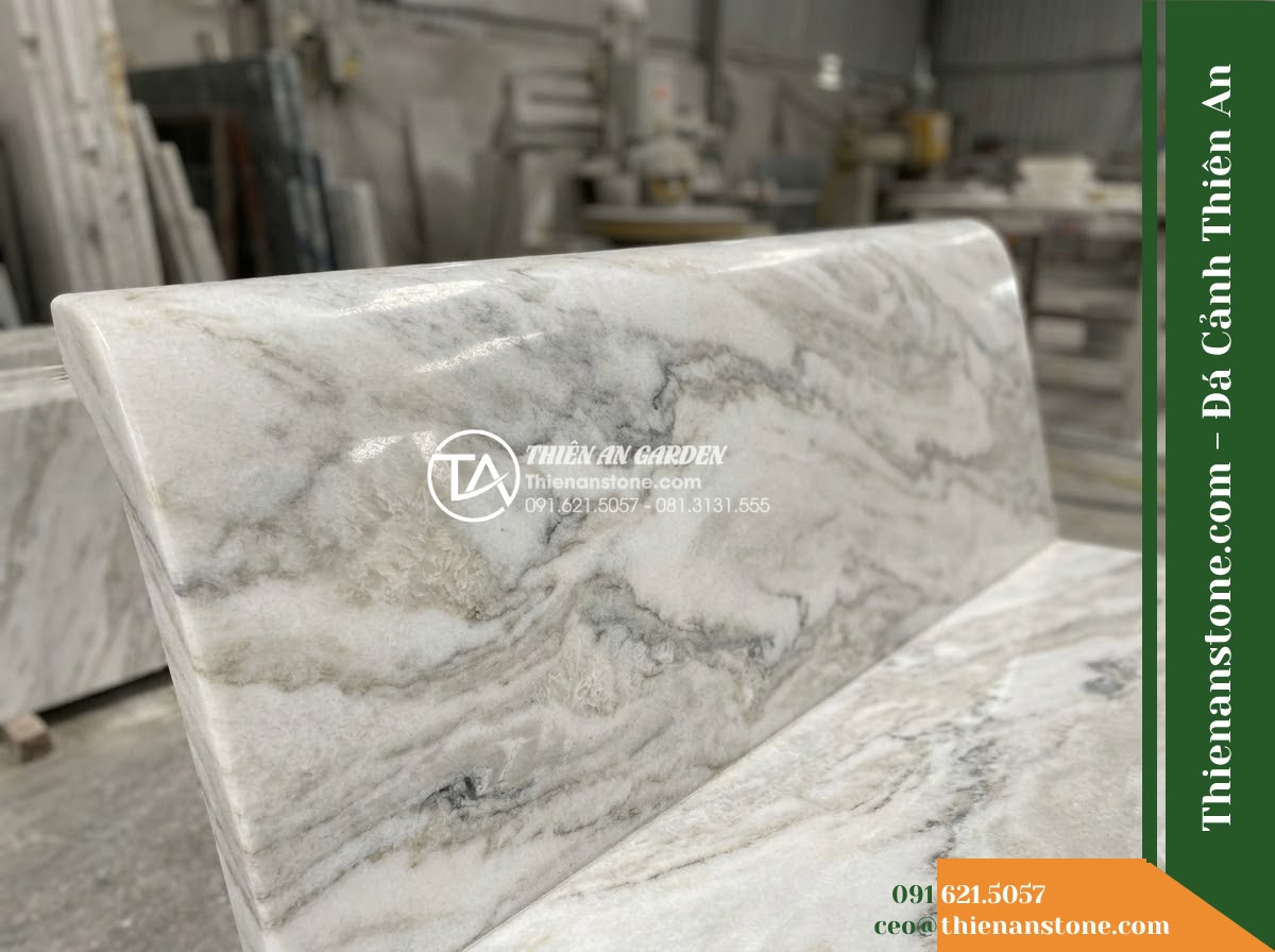 Ghế Đá Sân Trường Vững Bước – Kích thước 175 x 48 x 80 cm – Kiểu dáng tựa cong thấp, hai đầu vuông. Chất liệu đá vân mây - Hình 5 Ghế Đá Sân Trường Vững Bước – Kích thước 175 x 48 x 80 cm – Kiểu dáng tựa cong thấp, hai đầu vuông. Chất liệu đá vân mây - Professional installation of a cloud marble stone bench in a landscaped garden,