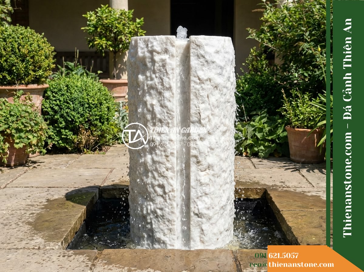 Trụ Phun Khối Thô Bổ Đôi Rãnh Nước, D45cm Cao 1m - Hình 5 Trụ Phun Khối Thô Bổ Đôi Rãnh Nước, D45cm Cao 1m - A wide landscape shot of the split natural stone fountain in a courtyard setting