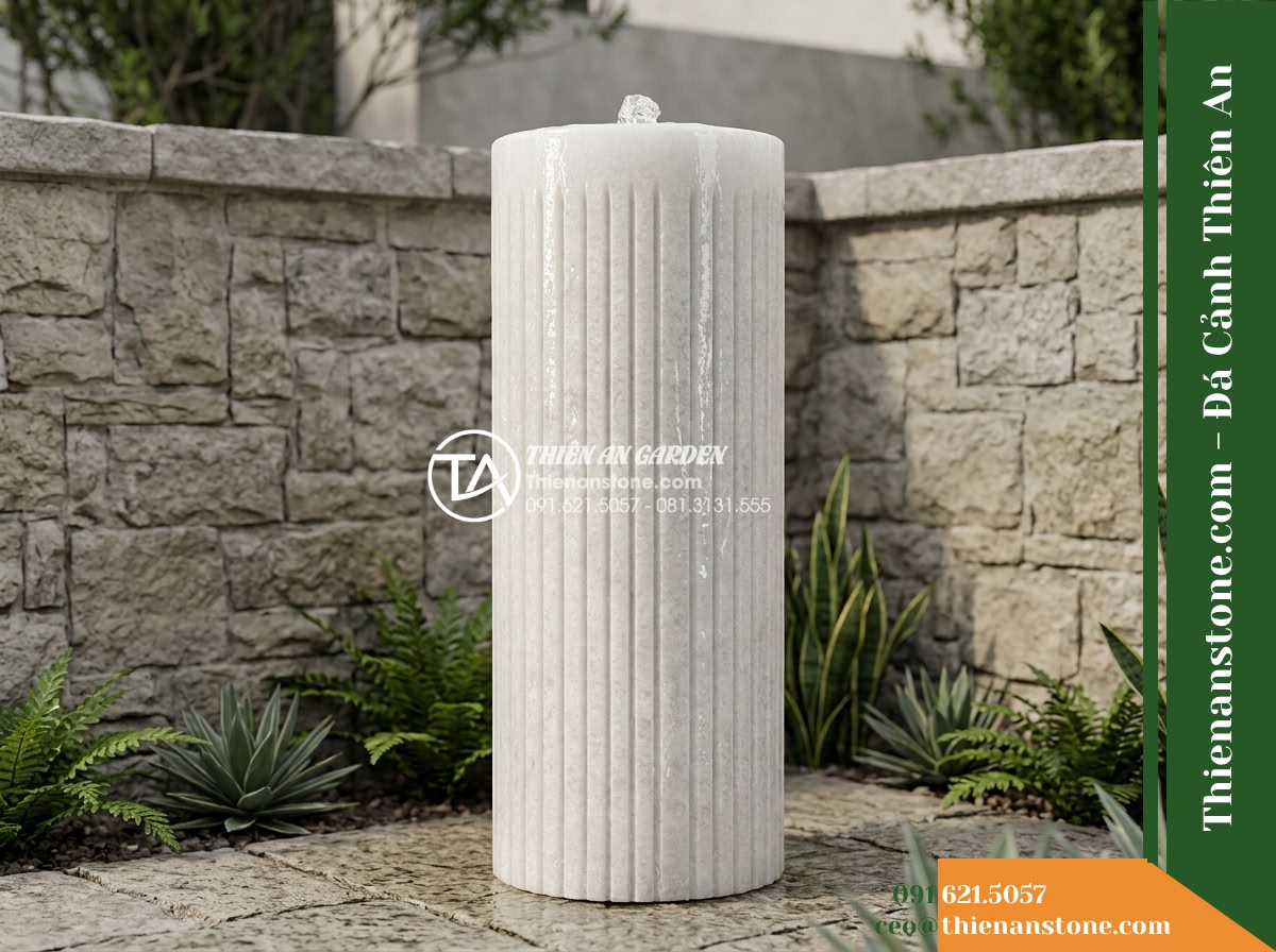 Trụ Phun Tròn Xẻ Rãnh Dọc Thân, Mài Mịn D35cm Cao 1m - Hình 5 Trụ Phun Tròn Xẻ Rãnh Dọc Thân, Mài Mịn D35cm Cao 1m - Wide view of a 1-meter high stone fountain column placed against a courtyard bou